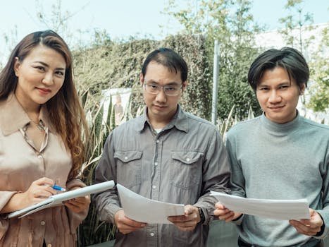 pexels-photo-7651952-7651952 Three colleagues discussing work documents in an outdoor setting, fostering teamwork.